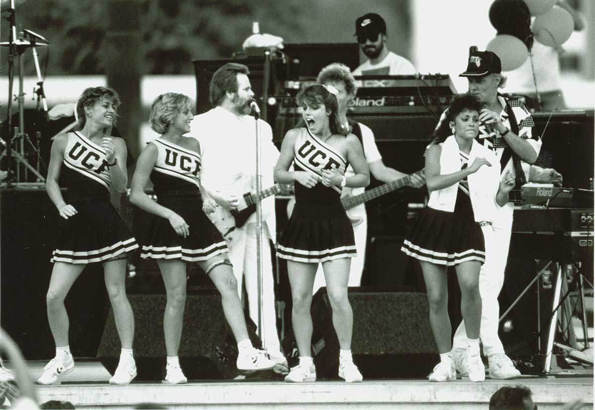 black and white photo of UCF cheerleaders on stage with Beach Boys