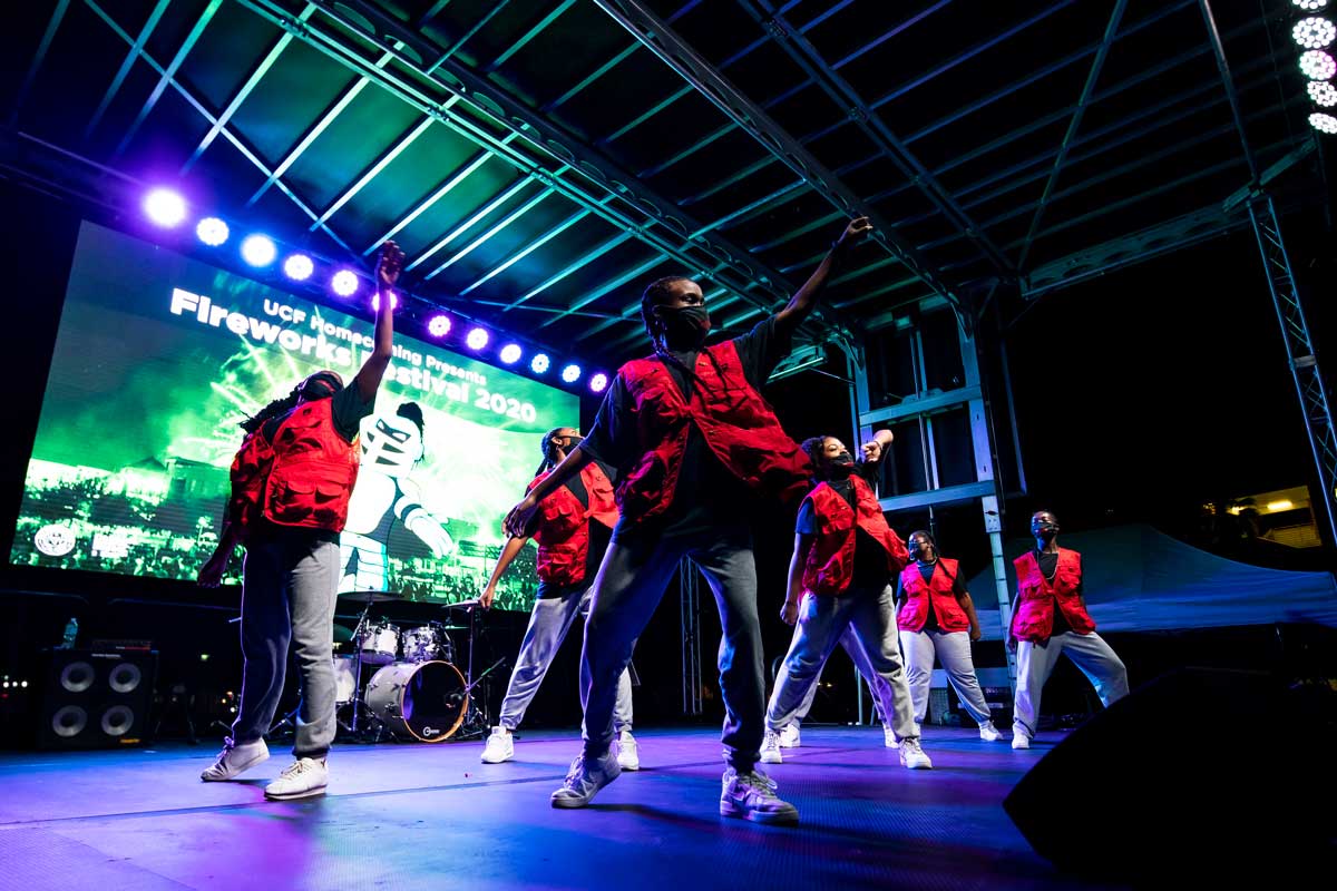 Group of dancers wearing red vests on stage