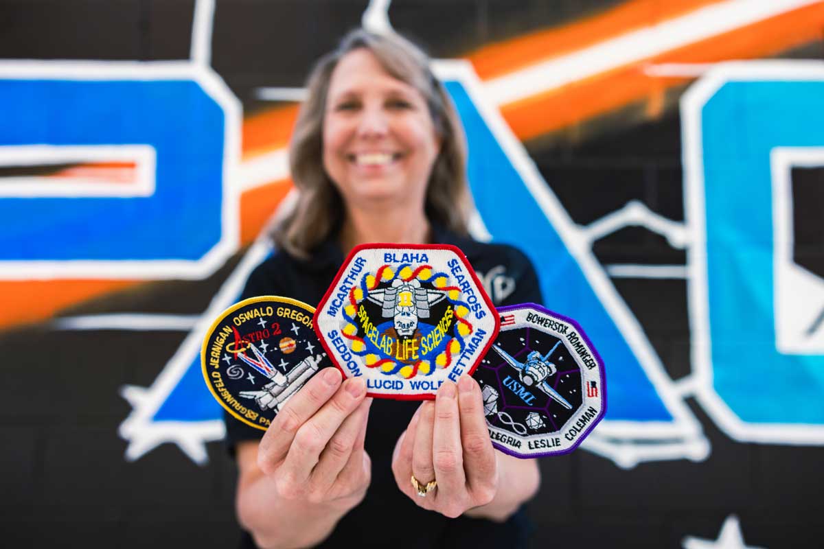 Sharlene Martin holds up three patches from space shuttle missions