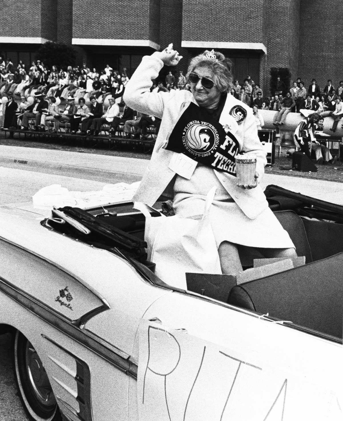 Woman sitting on back of convertible throws treats to crowd during parade