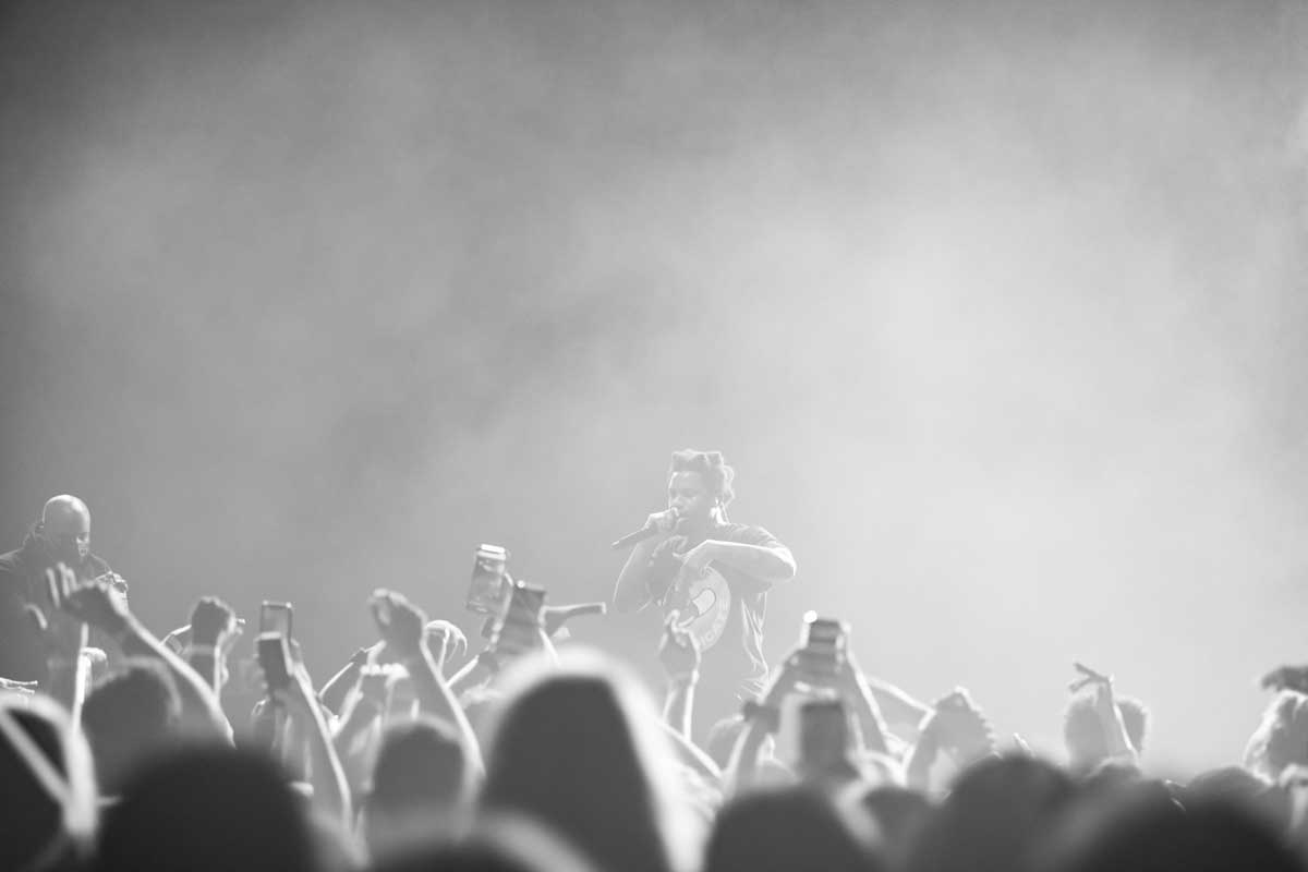 black and white photo of performer on stage in haze with crowd in front of him