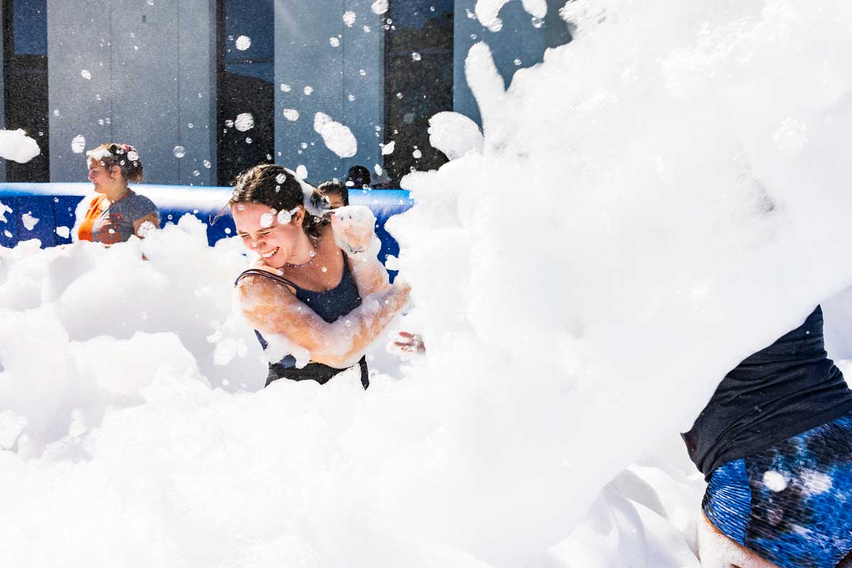 Young woman laughs as she pushes away foam from her face 
