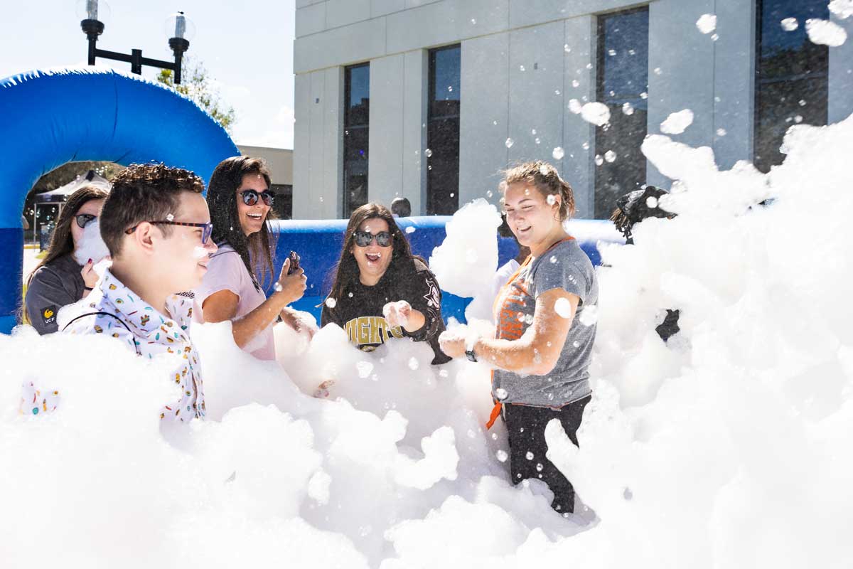 A group of college students laugh while walking through foam
