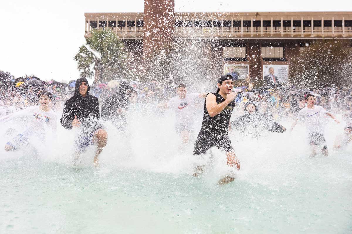 Students run into the Reflecting Pond as water sprays