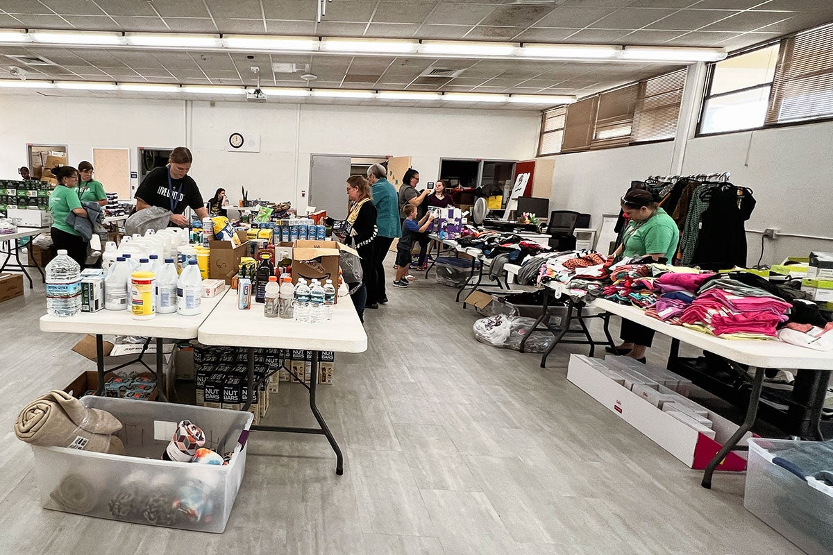 A room full of clothing, cleaning and food supplies with a group of volunteers
