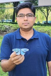UCF nanoscience researcher shows a metal buttterfly painted with the UCF-developed plasmonic paint