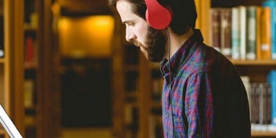 male ucf student profile looking at laptop while wearing headphones