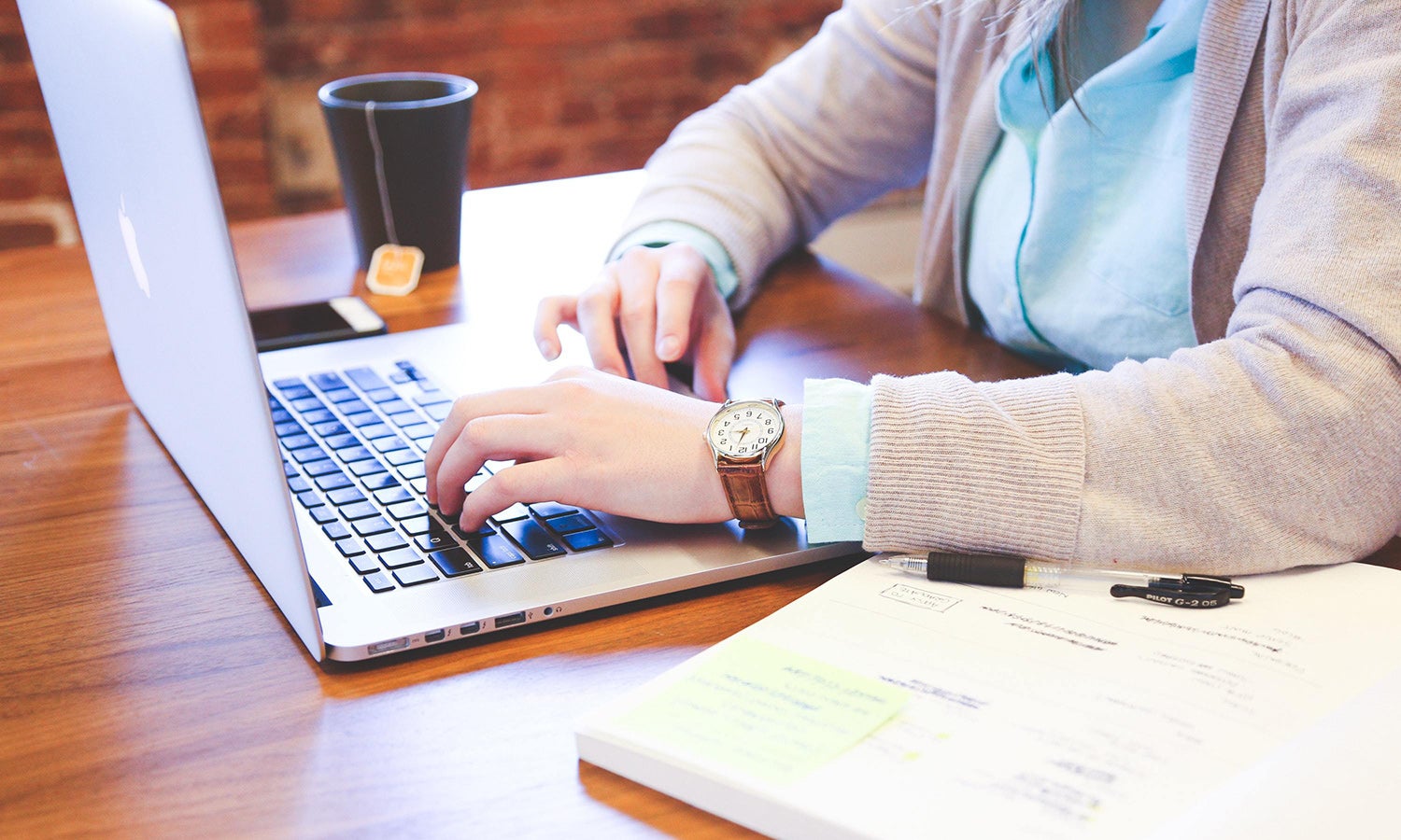 Woman in a blue shirt using and Apple laptop to complete an online course.