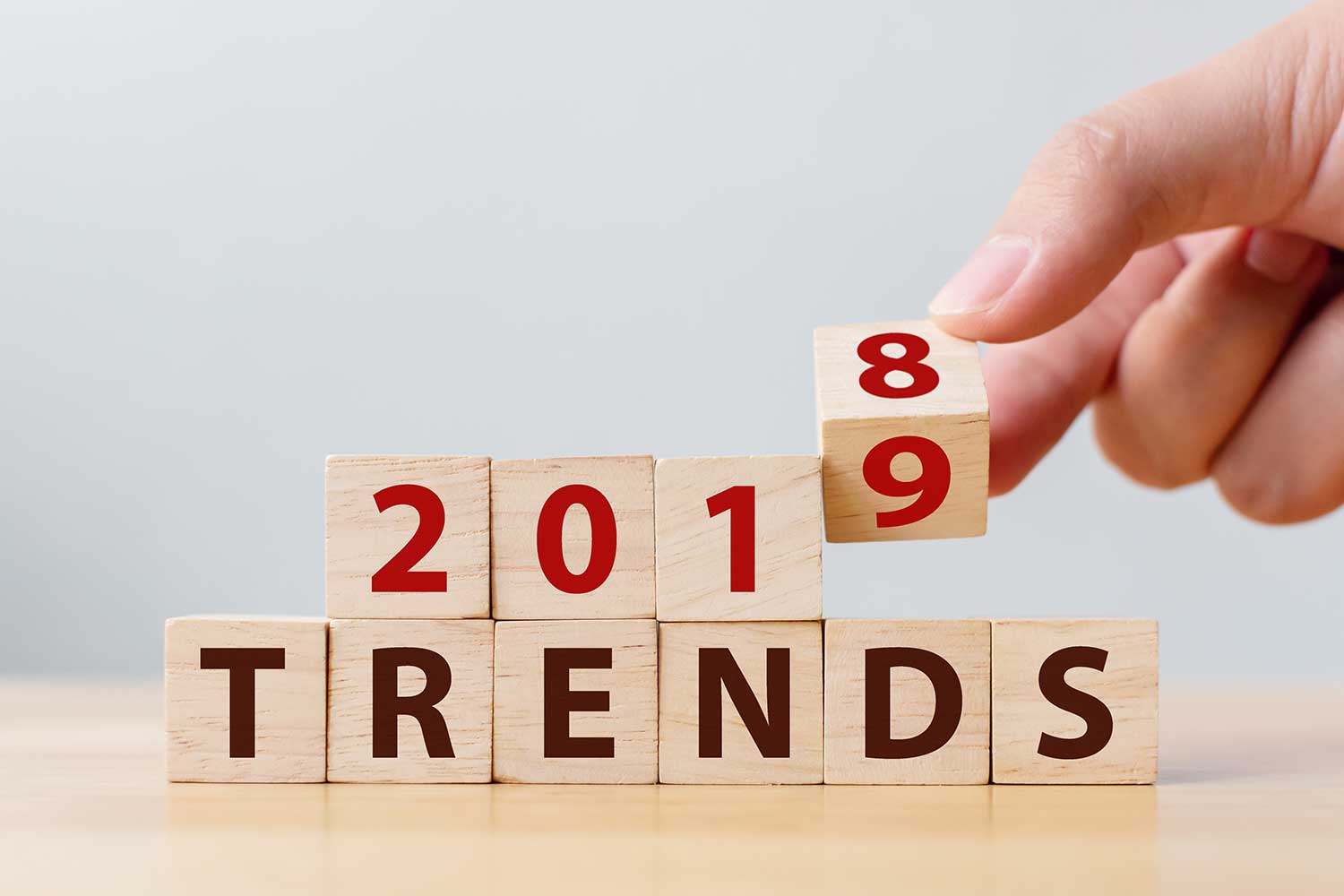 Hand flipping a a block for 2018 to 2019 over a line of blocks that spell out the word trends.
