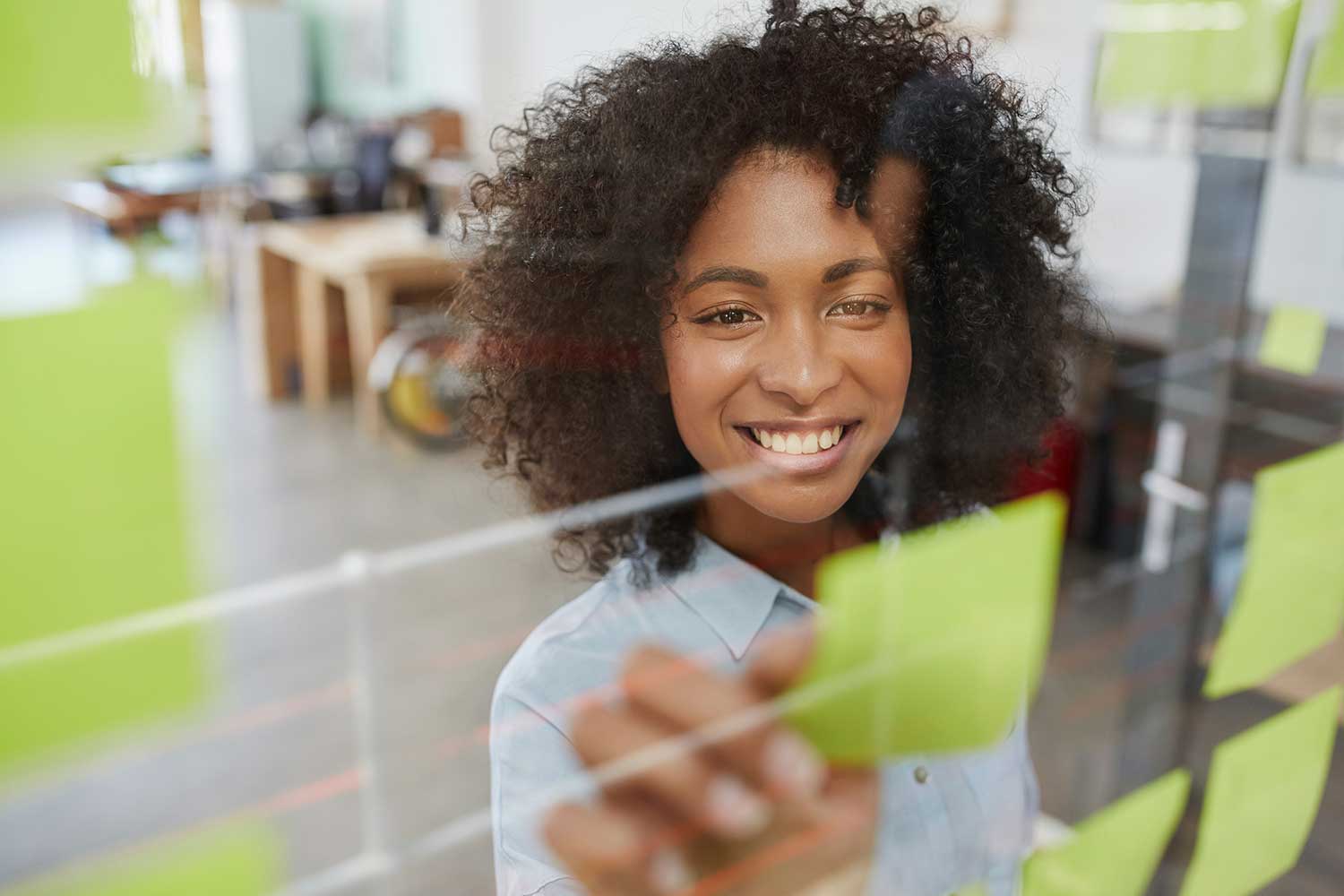 Woman organizing sticky notes on a clear board.