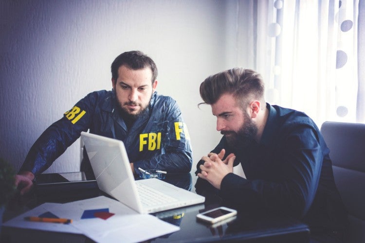 A digital forensics investigator examines a computer for the FBI.
