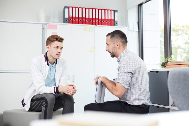 A juvenile probation officer meets in the probation office with a teenage client.