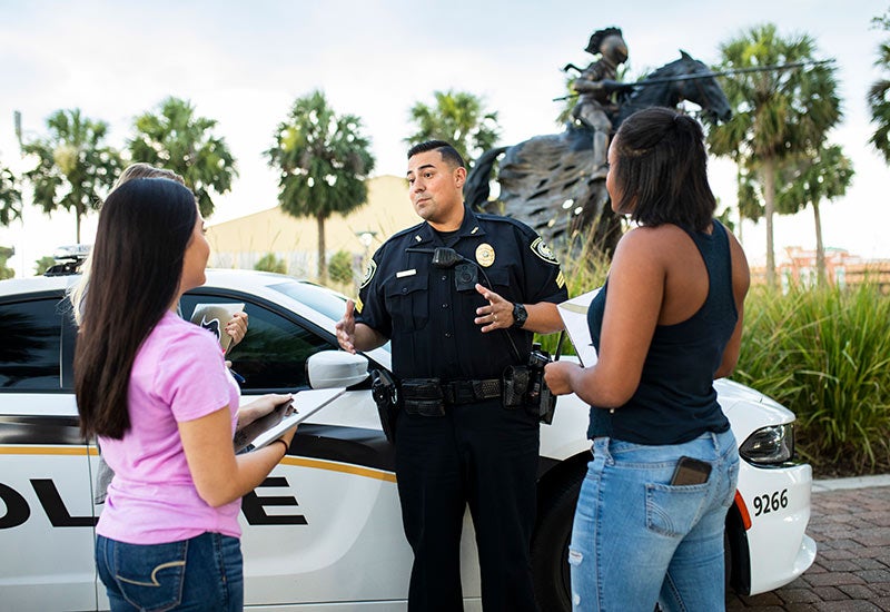 A police officer stands next to a police car.