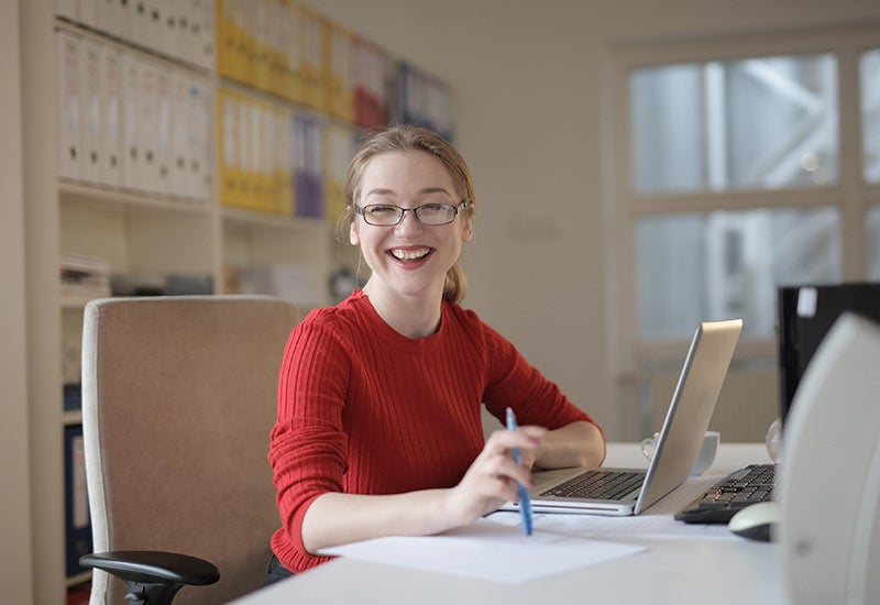 Research administrator in front of a laptop with logs of research behind her.