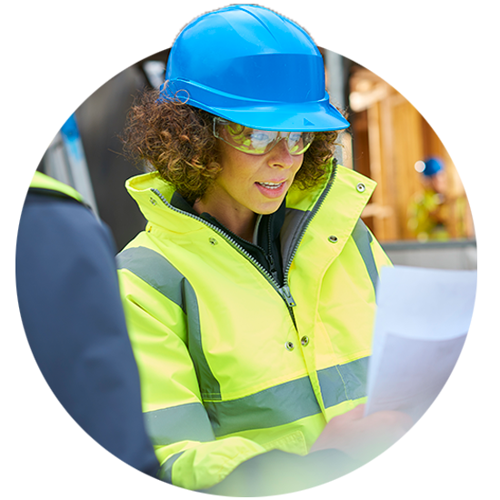 Woman in a hard hat and construction clothing looking at papers