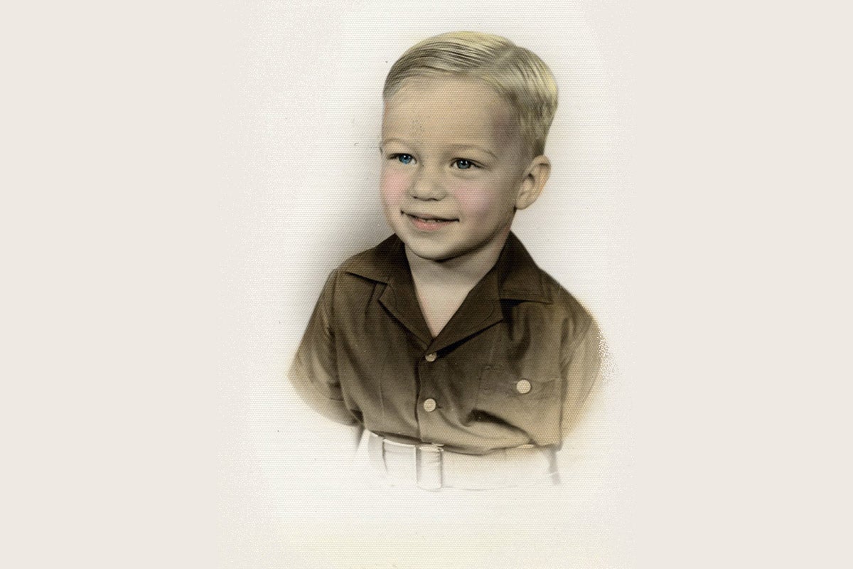 A colorized black and white photo of young white boy with blonde hair, blue eyes, and rosy cheeks wears a brown button-up shirt. A colorized black and white photo of young white boy with blonde hair, blue eyes, and rosy cheeks wears a brown button-up shirt.
