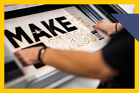 pair of hands hold sign that reads MAKER space