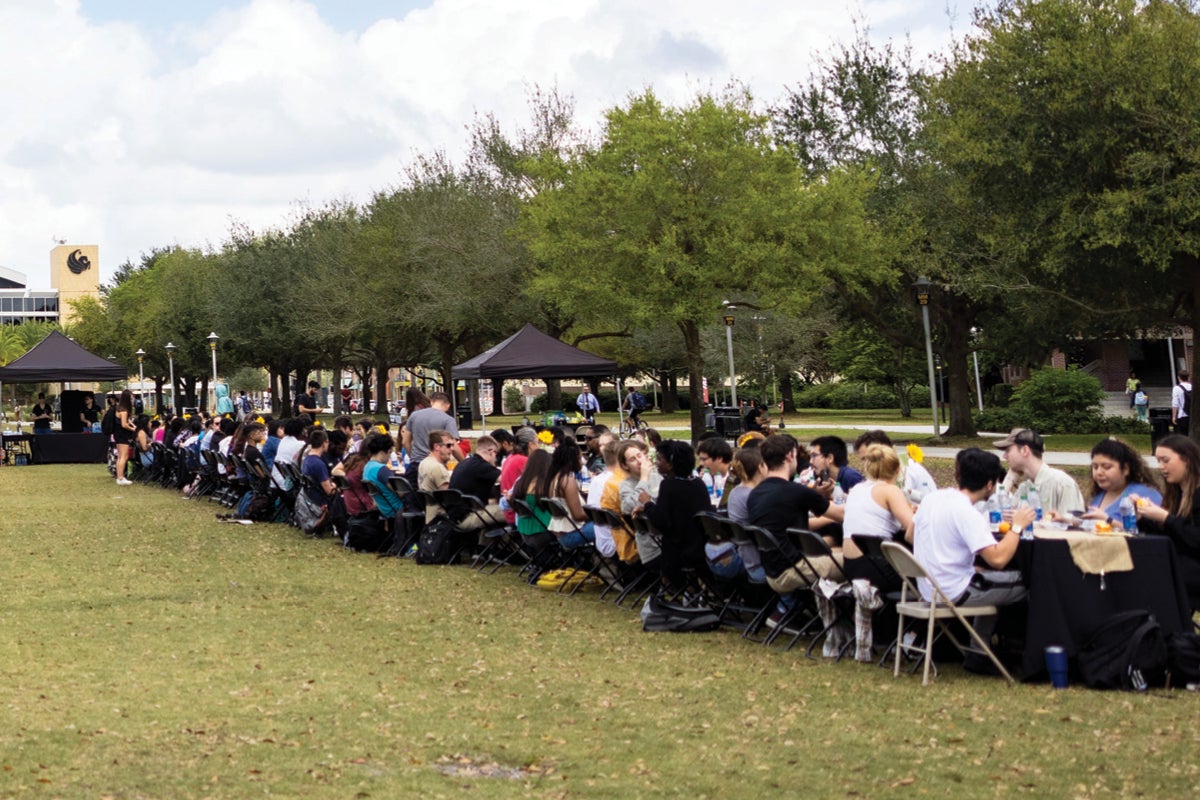 Students eating at a long table outside.