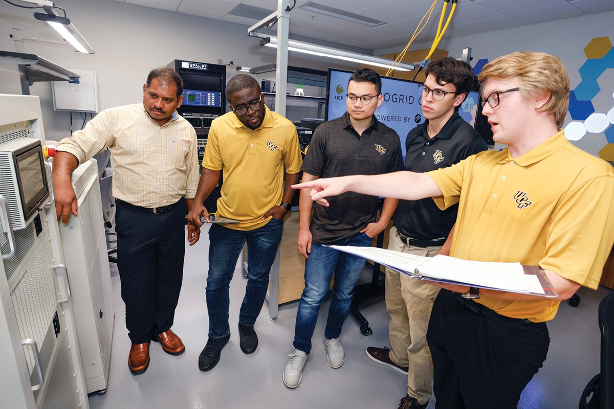 A staff member and students examine equipment in the UCF Microgrid Control Lab.