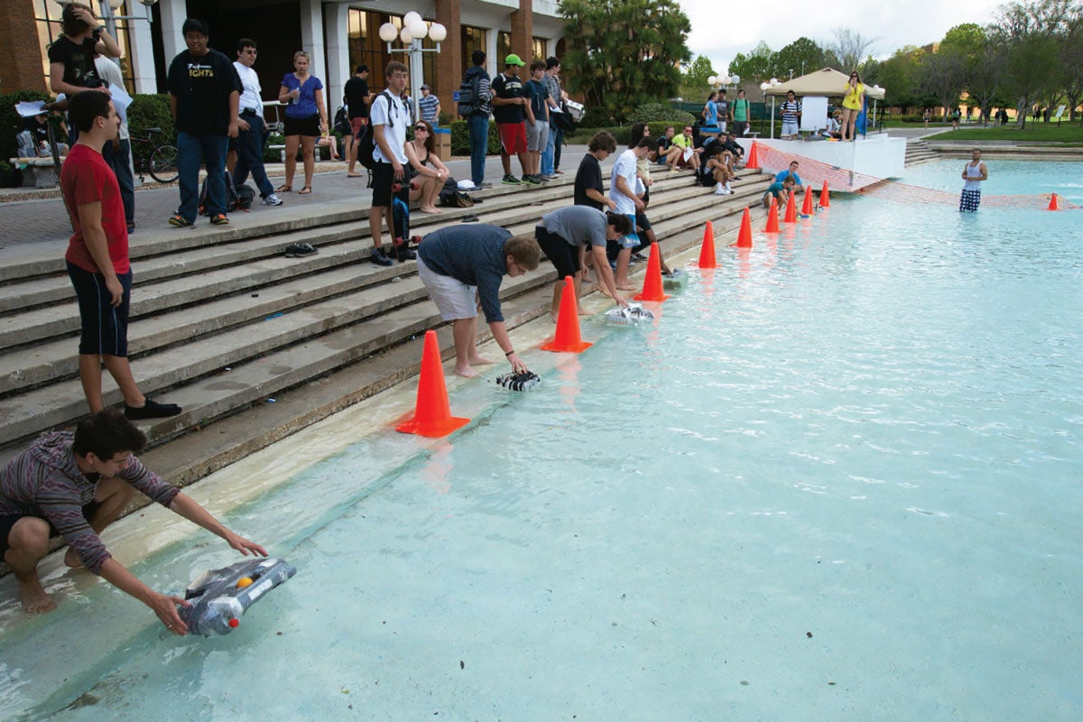 Students placing their watercraft in the UCF reflecting pond to start the race.