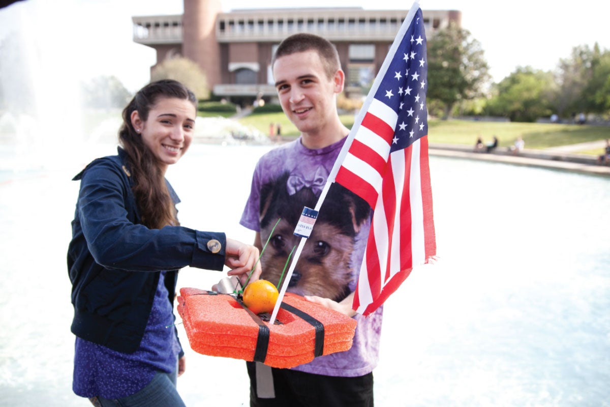 Two students working on their watercraft in front of the UCF reflecting pond.