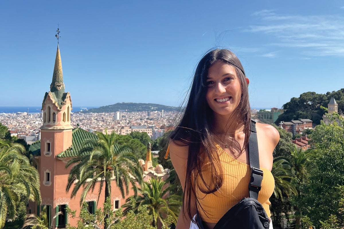 A student poses for a photo with building in the background