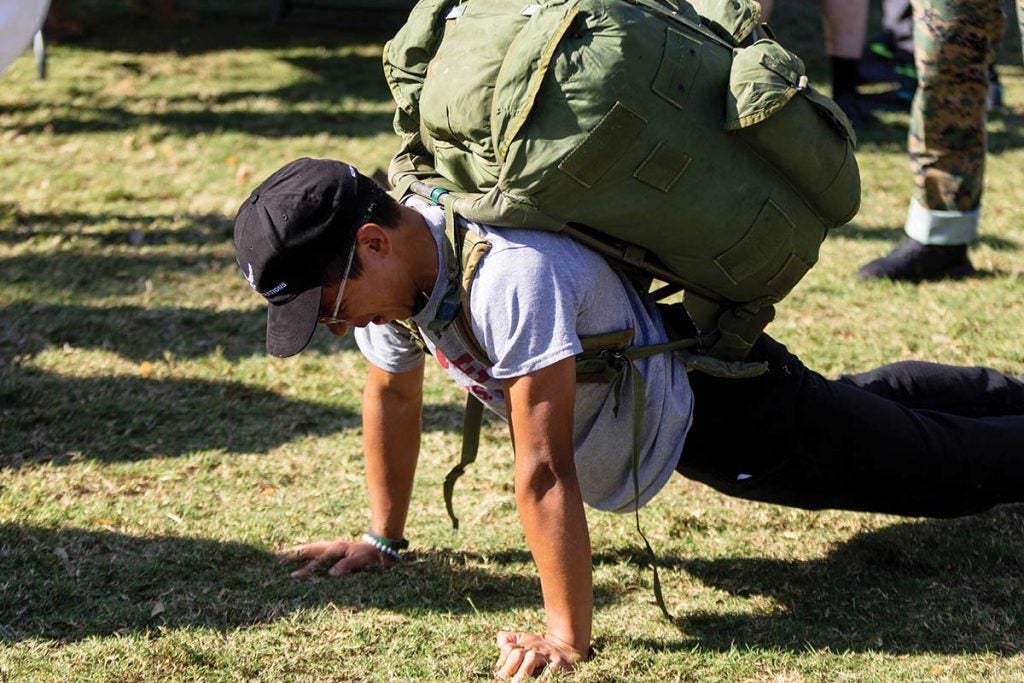 A man does a push-up while wearing a large backpack