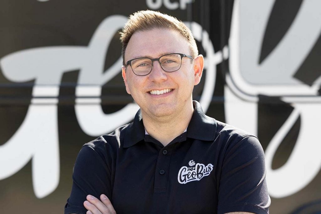 Headshot photo of UCF Associate Professor and GeoBus founder Tim Hawthorne who is wearing glasses and a black collared shirt, and is also looking straight ahead while smiling.