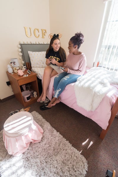 two students chat in a residence hall with pink decor