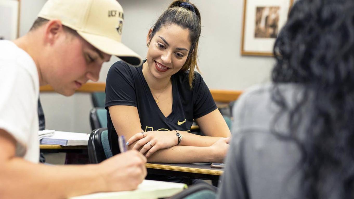 Students study together while sitting in classroom desks. 