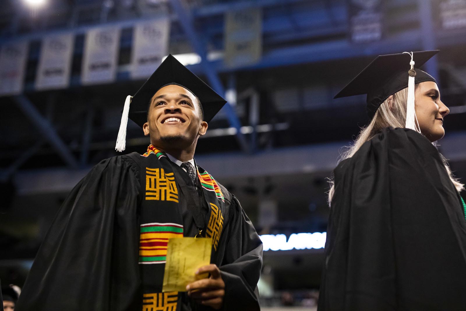 Male student wearing cap and gown during commencement inside the Addition Financial Arena. 