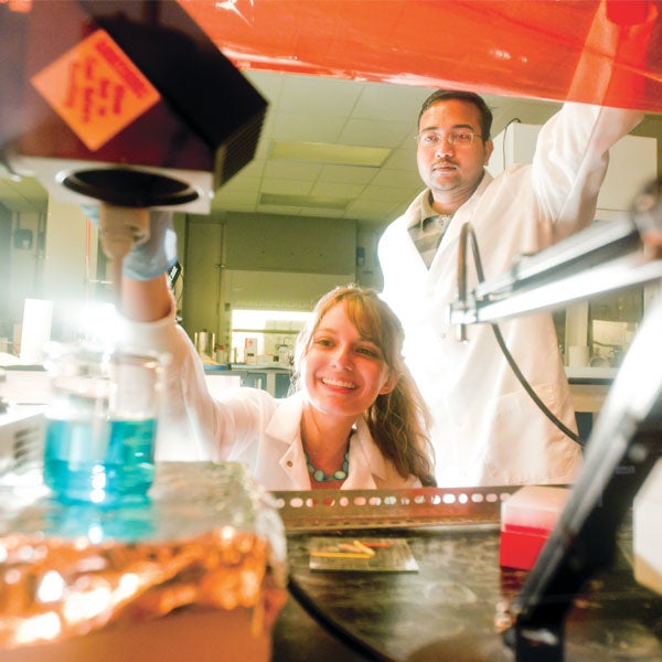 male and female ucf students in white lab coats working in a lab