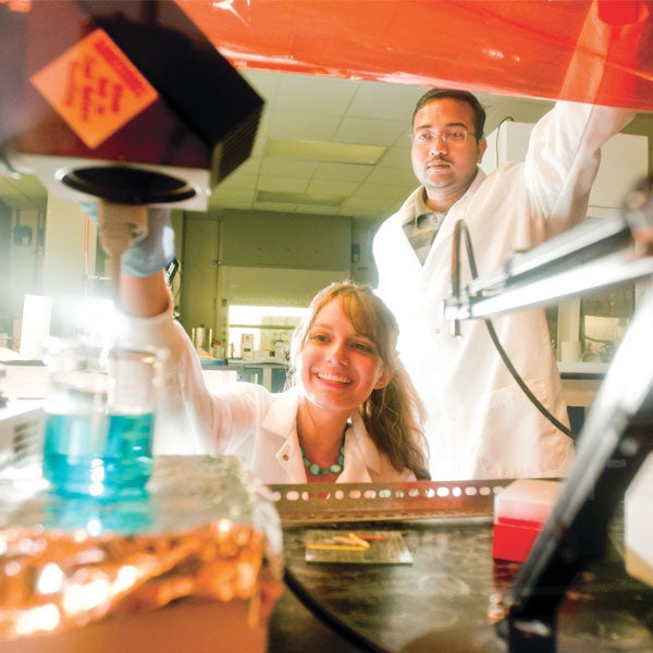 ucf students in white lab coats working in a lab