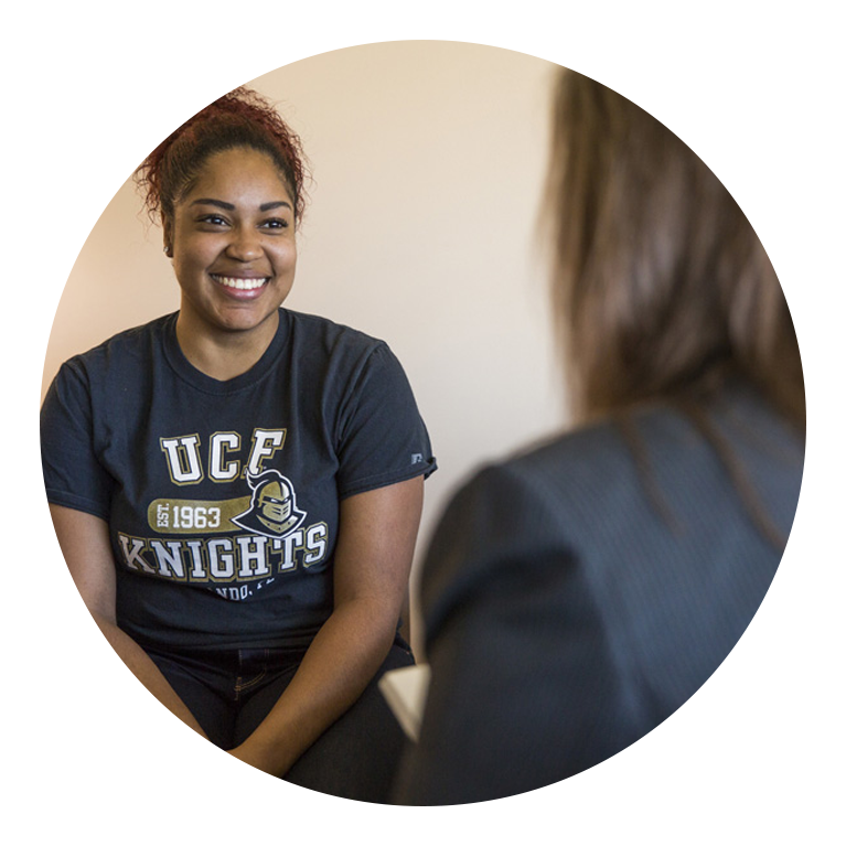 Woman student wearing UCF shirt talking to another individual