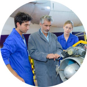 Two UCF students and instructor repair a jet engine