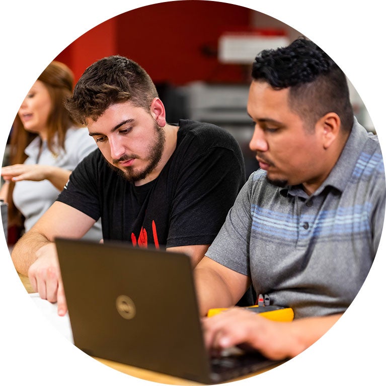 Two civil engineering students sitting a table, working on a laptop