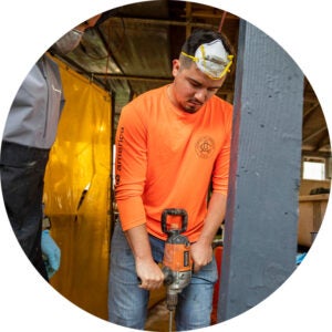 Worker using a jackhammer in a construction training area.