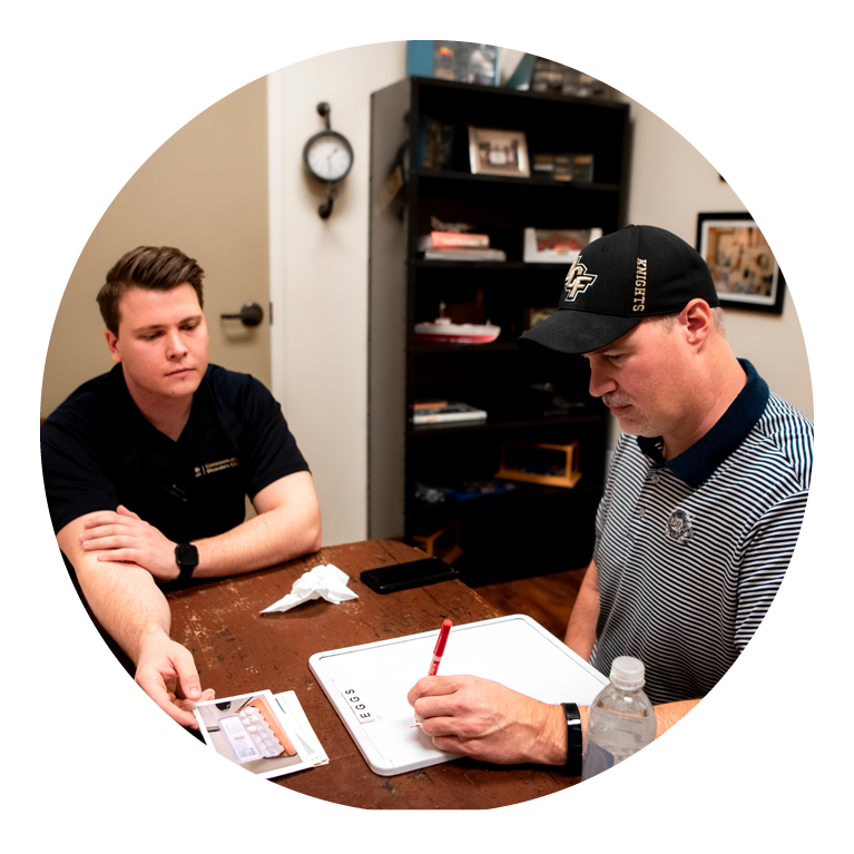 Two men working on a dry-erase board