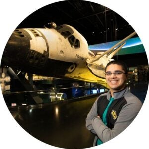 UCF Alum stands next to NASA Space Shuttle at Kennedy Space Center