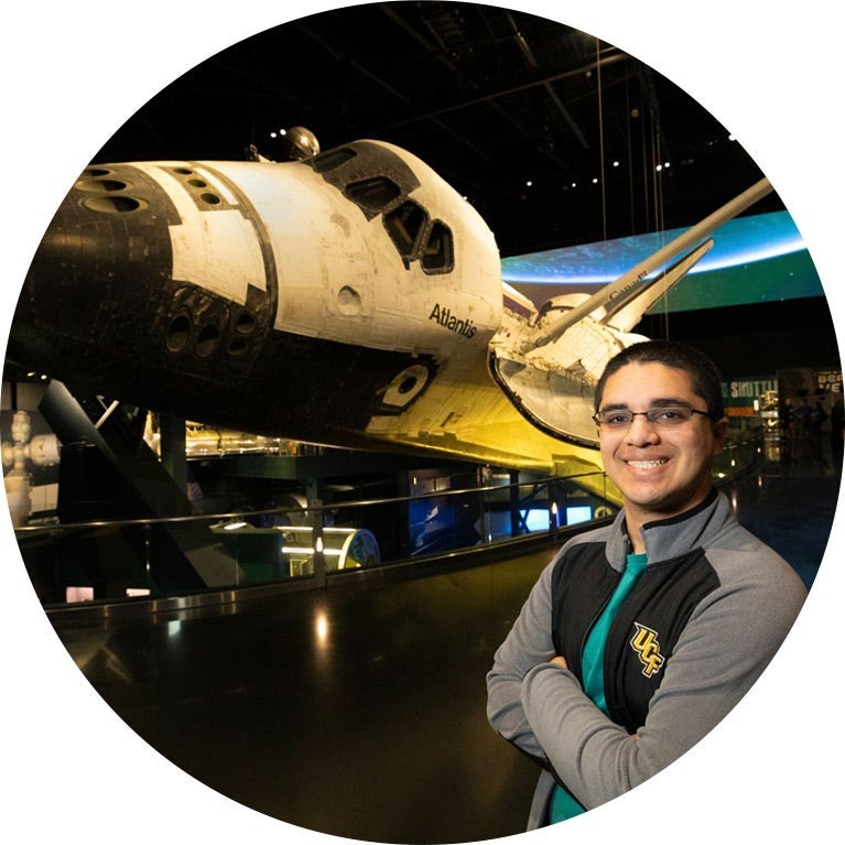 UCF Alum stands next to NASA Space Shuttle at Kennedy Space Center