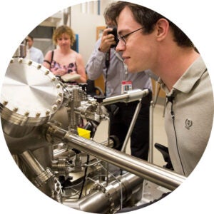 Man examining a stainless-steel scientific instrument in a lab.