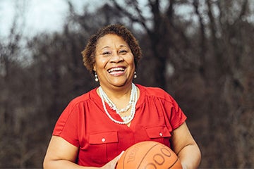 Marcie (Swilley) Washington is pictured smiling while standing outside holding a basketball