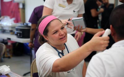UCF health sciences student takes checks patient's temperature at a health fair
