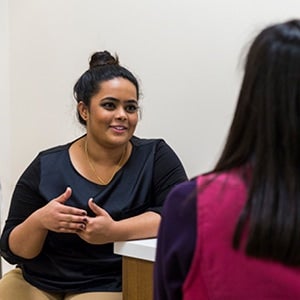 Woman standing next to a counter talking to another woman.