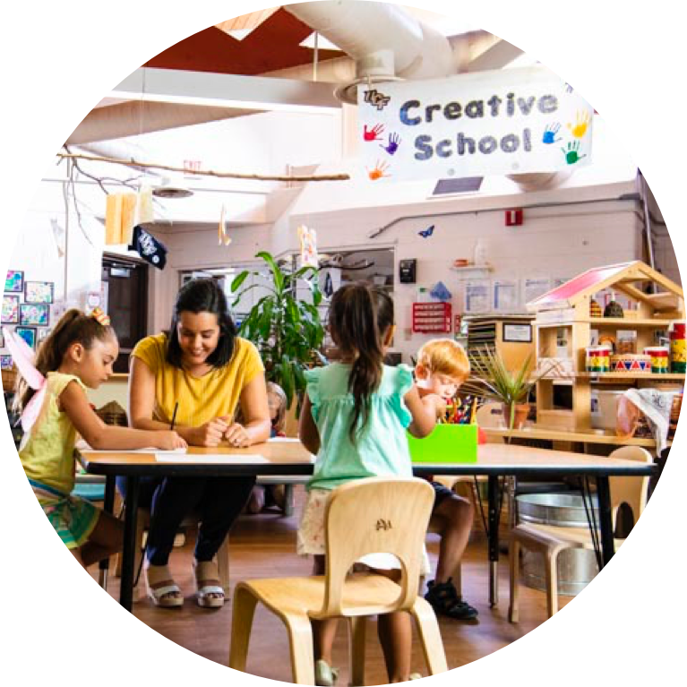 Teacher sitting at table with young students.