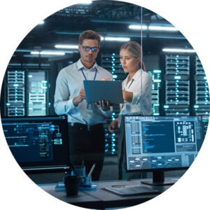 Two IT professionals reviewing a laptop in a data center.