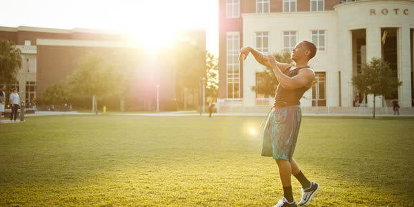 Male studnet throwing football on Memory Mall