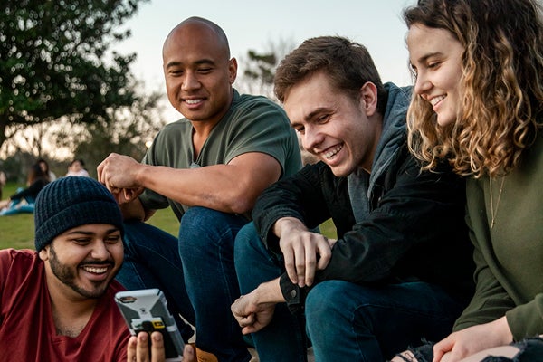 Students sitting together looking at one student's cell phone and smiling