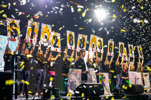 Individuals holding up signs that visualize the amount of money raised during Knight-Thon