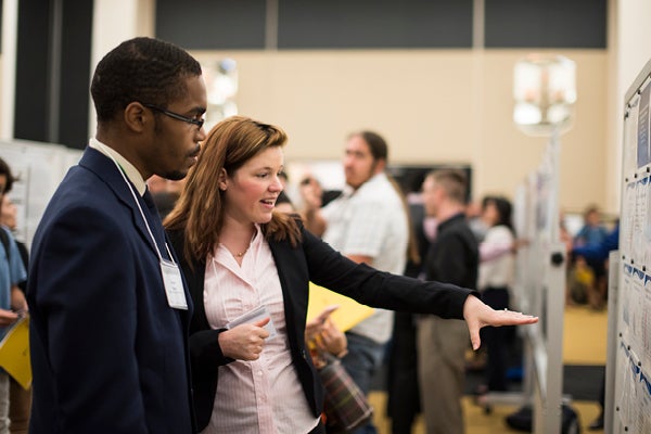 Two individuals talking and looking at a project during Student Research Week